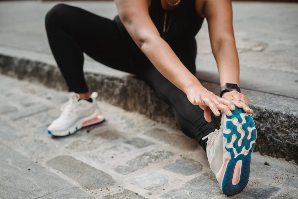 pexels photo 5036892 A woman in athletic apparel stretching on an urban sidewalk for fitness and flexibility.